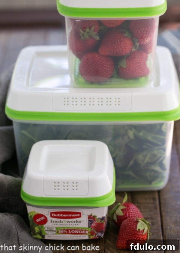 Strawberry Bacon Brie Salad ingredients, including strawberries and spinach, stored in clear plastic produce saver containers.