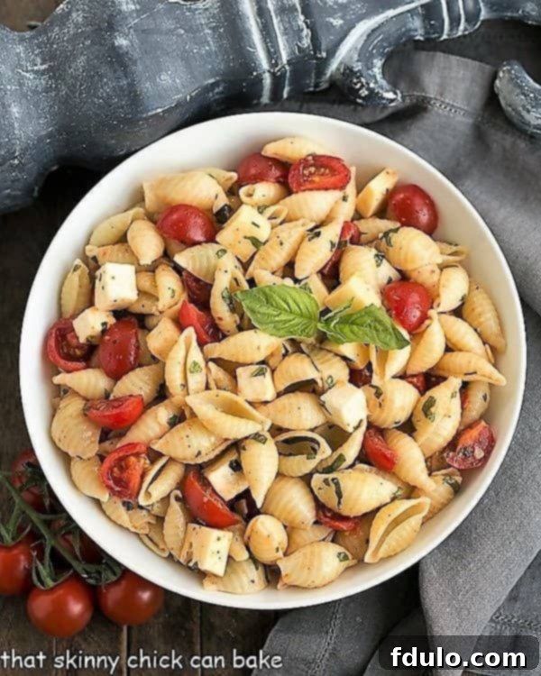 An inviting overhead view of Tomato Basil Pasta Salad with Mozzarella & Fontina, showcasing its colorful ingredients in a pristine white serving bowl.