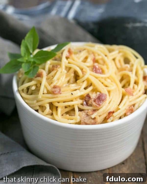 Spaghetti Carbonara Recipe: Pasta combined with grated cheese, eggs and pancetta create a simple, delectable entree A white ceramic bowlful of spaghetti carbonara, ready to be enjoyed.