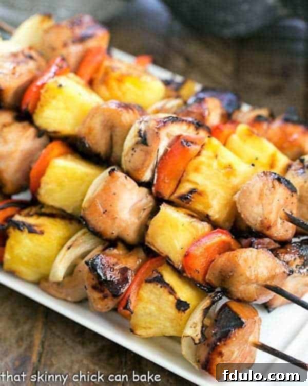 Honey Glazed Chicken Kabobs - Marinated chicken, veggies and pineapple are grilled to perfection! Skewered Honey Glazed Chicken Kabobs beautifully arranged on a white platter, ready for serving.