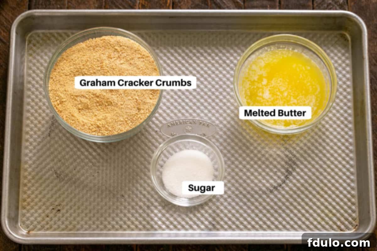 Ingredients for a homemade graham cracker crust laid out on a sheet pan, including graham cracker crumbs, sugar, and melted butter.