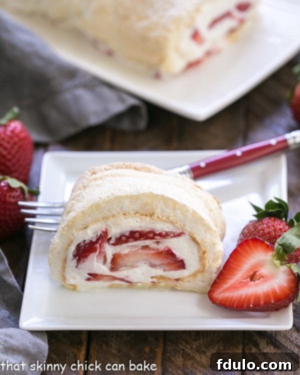 Strawberry Meringue Roulade - A simple baked meringue rolled with fresh strawberries and cream! Strawberry Filled Meringue Roulade slice on a white dessert plate, showcasing the light meringue, cream, and berries