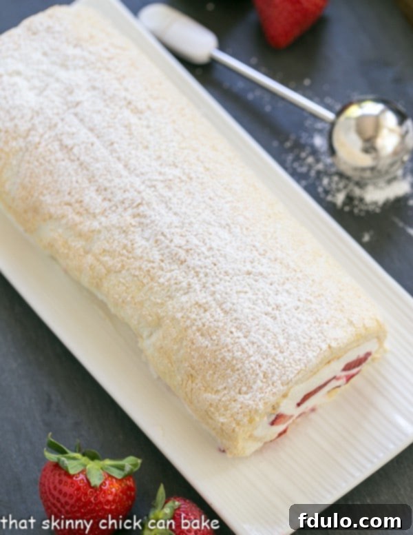 Elegant Meringue Roulade - A simple baked meringue rolled around fresh strawberries and cream! Strawberry Filled Meringue Roulade on a white ceramic serving tray, highlighting its elegant presentation