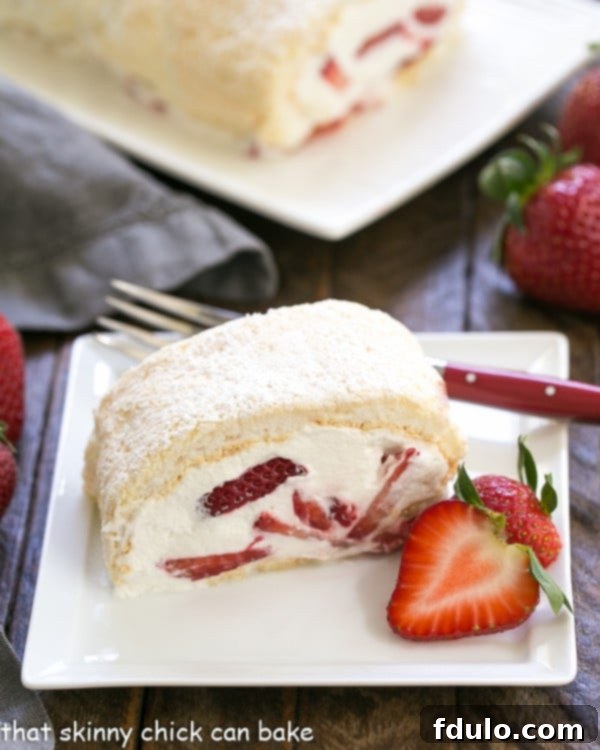 Delicious Strawberry Meringue Roulade - Fresh strawberries and cream in a light meringue roll! Close-up of a Strawberry Filled Meringue Roulade slice on a square white plate with a red handled fork and strawberry garnish