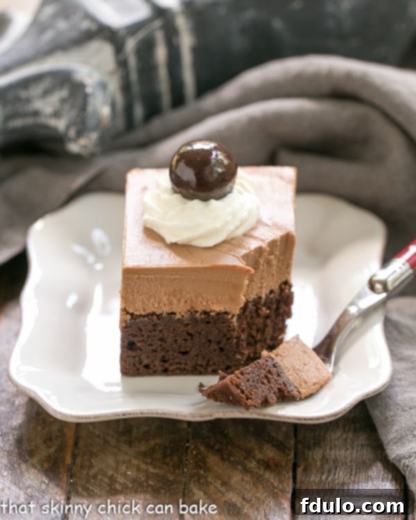 A French Silk Pie Brownie with a portion removed, resting elegantly on a square white plate, highlighting its luscious layers.