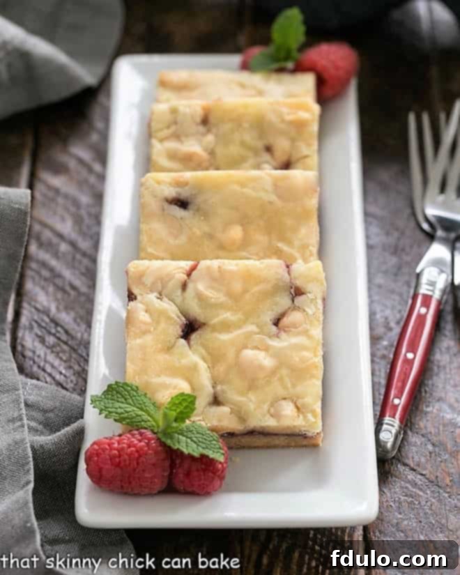 White Chocolate Raspberry Bars lined up on a rectangular white tray.