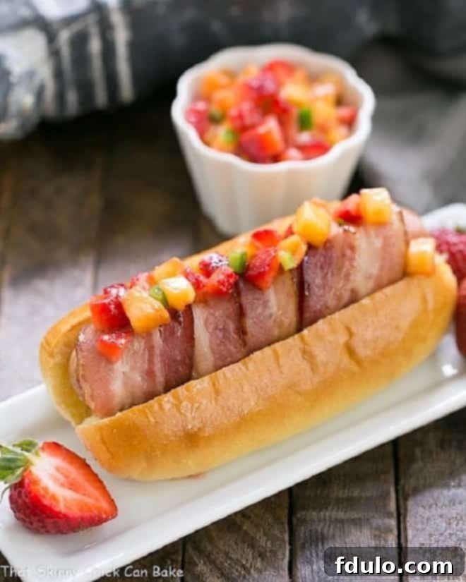 Bacon Wrapped Hot Dogs with Fruit Salsa on a narrow white ceramic plate.