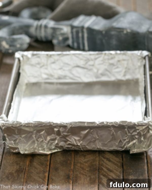 A baking pan meticulously lined with non-stick foil, ready to receive cookie dough or brownie batter, highlighting careful preparation for clean cuts.