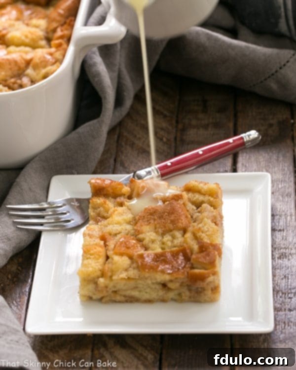 A rich stream of golden Whiskey Sauce being generously poured over a warm, inviting slice of Cinnamon Bread Pudding, promising a symphony of flavors.