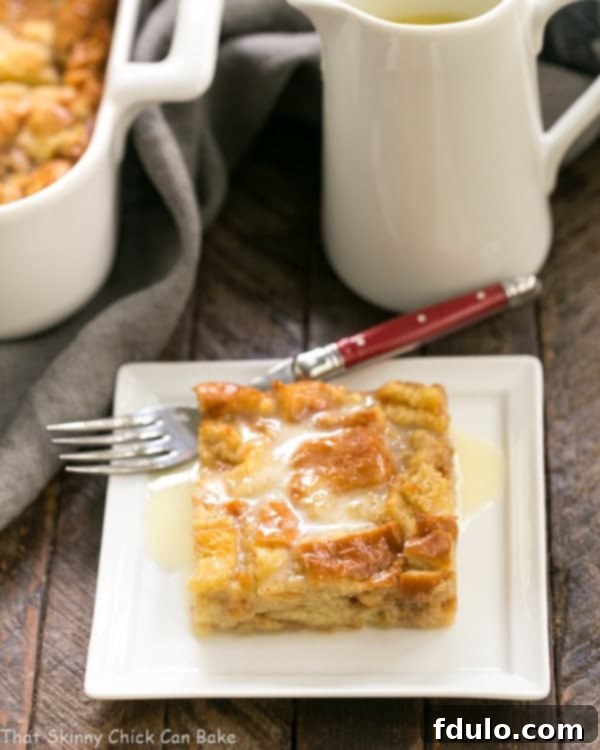 Another enticing close-up of a slice of Cinnamon Bread Pudding with Whiskey Sauce, artfully arranged on a square white plate, accompanied by a fork with a vibrant red handle, ready for tasting.