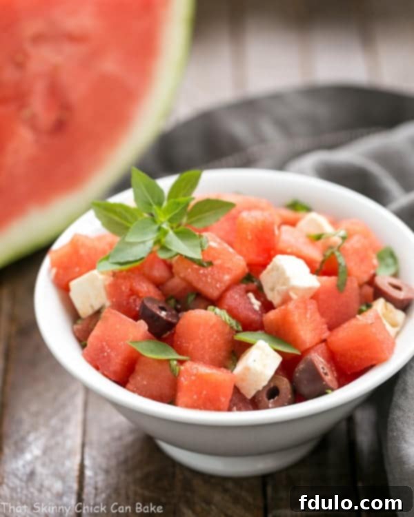 A vibrant Watermelon Feta Basil Salad with Balsamic Vinaigrette in a white bowl, garnished with fresh basil leaves.