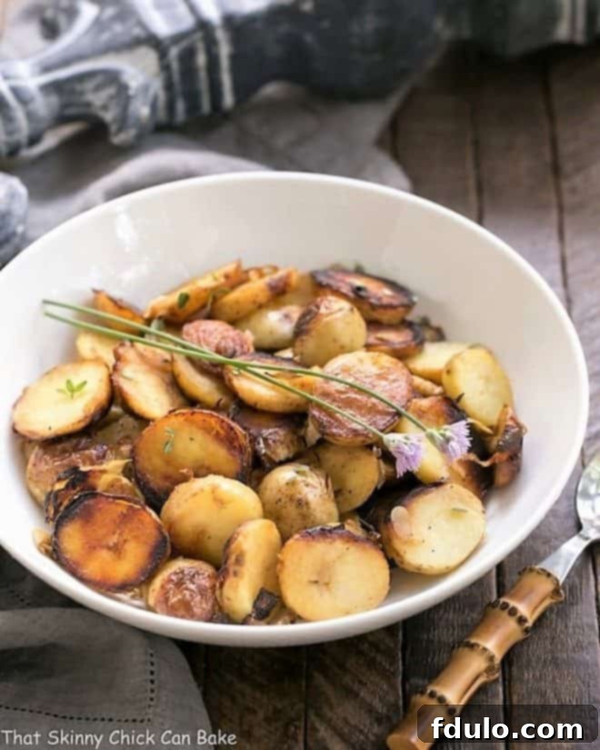 Close-up of golden-brown grilled potato packets with shallots and thyme, served in a white bowl with a bamboo-handled fork, ready to be enjoyed as a perfect summer side dish for any BBQ.