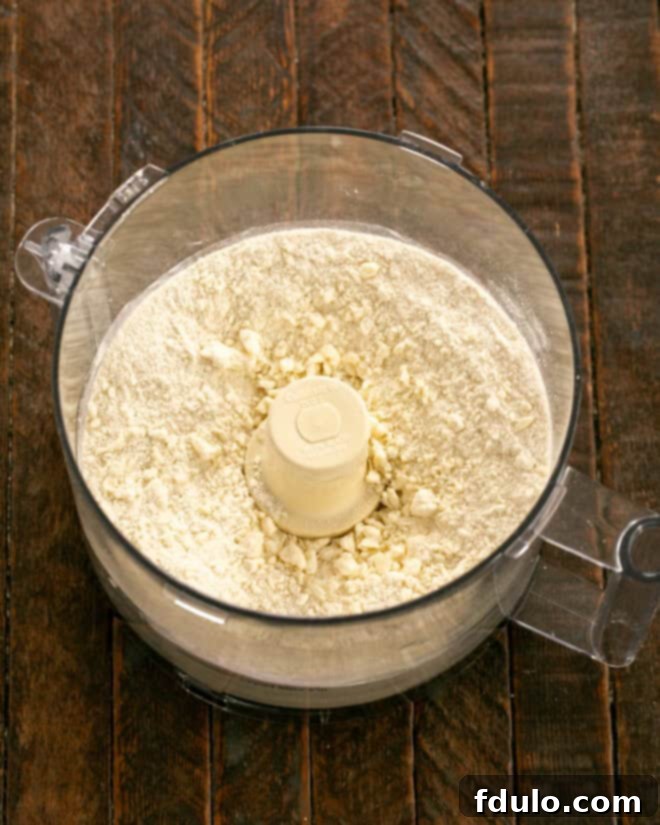 Galette crust ingredients, including flour, sugar, salt, cold butter, and cream cheese, in a food processor, ready to be pulsed.