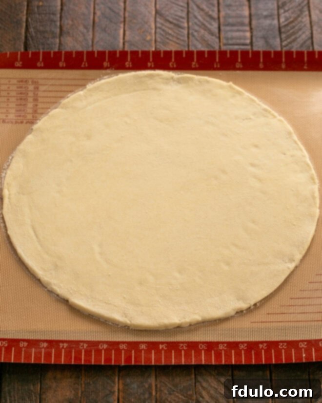 The apple galette crust, expertly rolled out into a large round shape on a Silpat baking mat, ready for the apple filling.