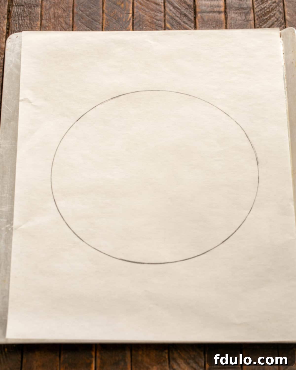 Parchment paper marked with a 9-inch circle for pavlova on a baking sheet.