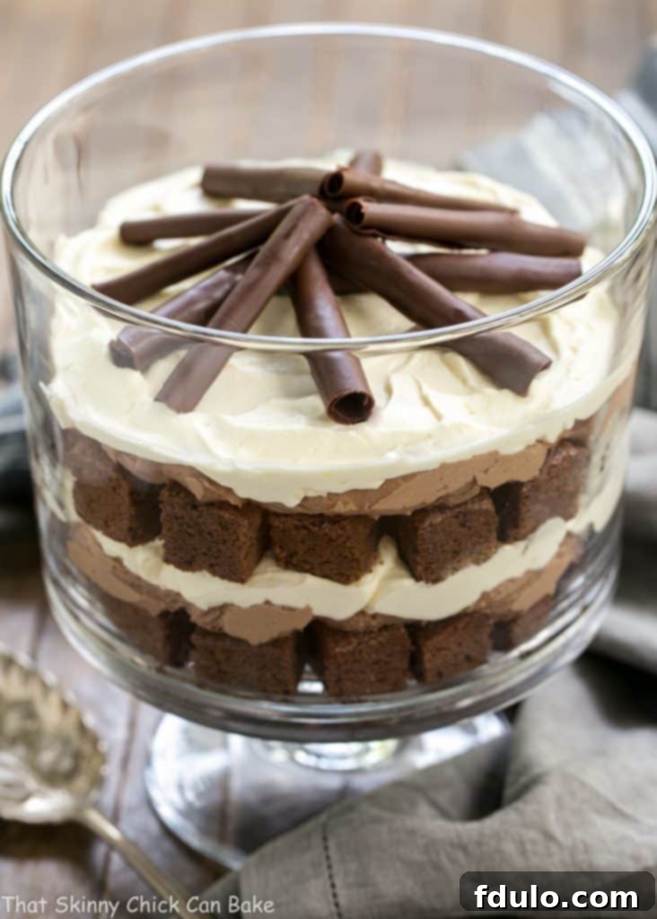 Fudgy Brownie Trifle with Chocolate Mousse - 3 outrageously delicious layers plus chocolate curls! A mesmerizing side view of the Fudgy Brownie Trifle, showcasing its distinct, delicious layers of dense brownies and creamy chocolate mousse, all within a clear glass trifle bowl.