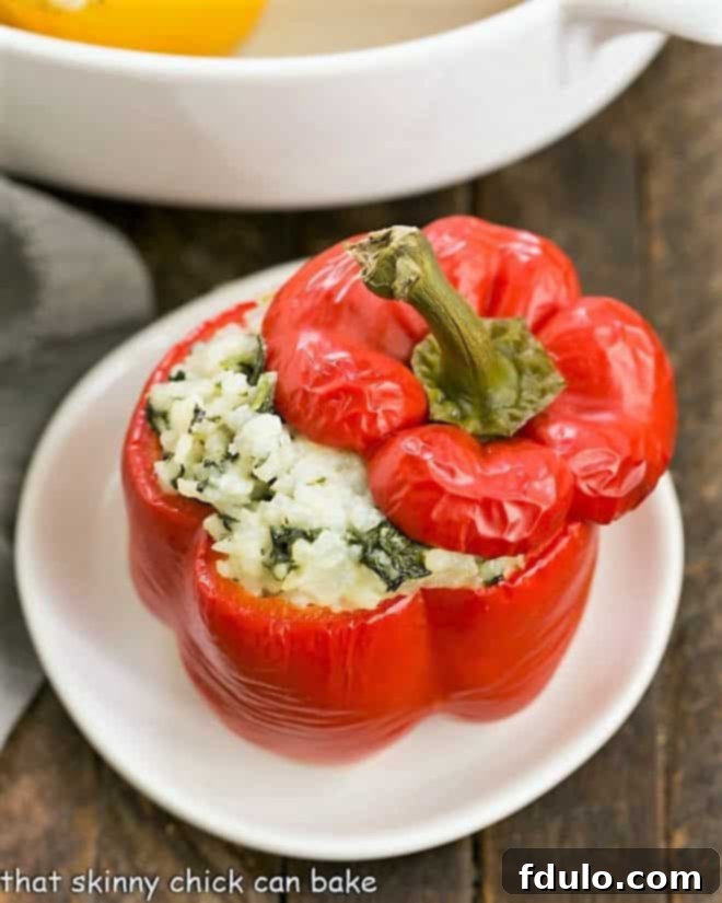 A single perfectly baked Rice Packed Pepper on a white ceramic plate, ready to be served, showing the golden cheese topping.