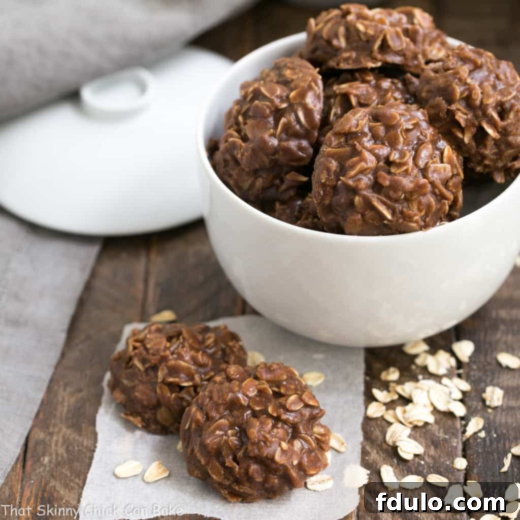 Classic Chocolate Peanut Butter No Bake Cookies in a white bowl with two cookies in the foreground.