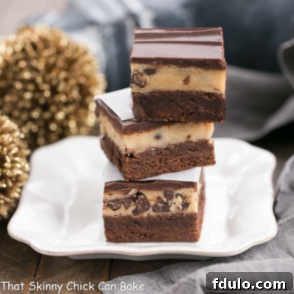 Stacked Chocolate Chip Cookie Dough Brownies on a white ceramic plate, ready to be served, highlighting their indulgent layers.