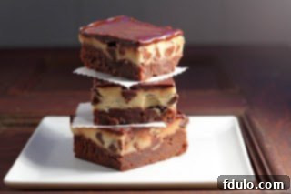 A beautifully presented stack of Chocolate Chip Cookie Dough Brownies on a white plate, showcasing all three layers of brownie, edible cookie dough, and ganache.
