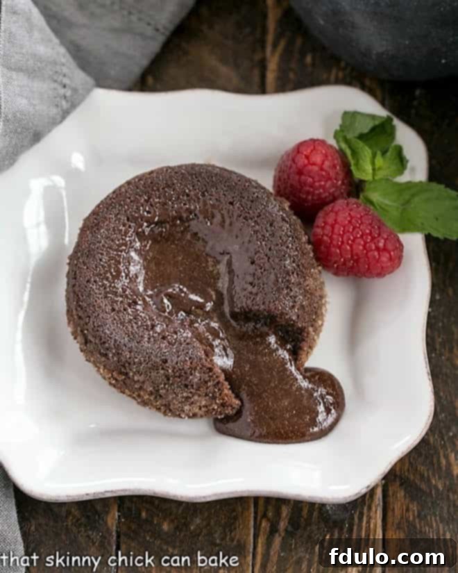 A perfectly baked molten lava cake on a white plate with a forkful revealing its rich, gooey chocolate center, garnished with a single raspberry.