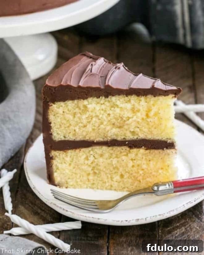 A slice of classic yellow butter cake topped with rich chocolate icing, presented on a white plate with a red-handled fork, ready to be enjoyed.