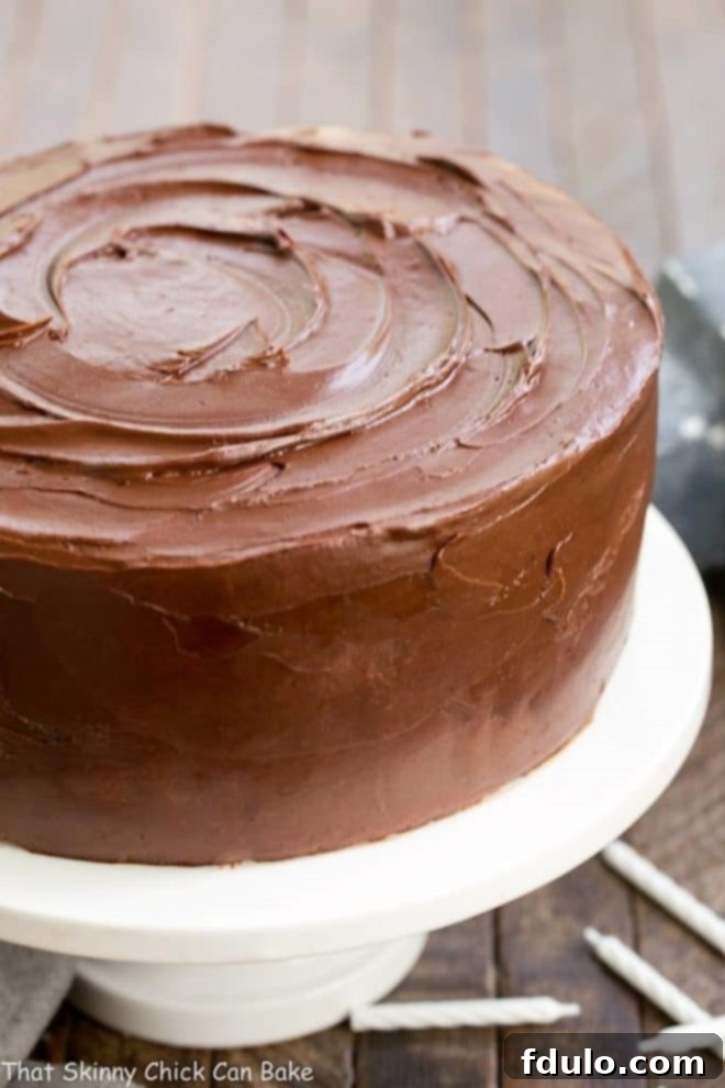 A stunning two-layer Classic Yellow Butter Cake, expertly frosted with rich Chocolate Icing, displayed on an elegant cake platter, ready to be served.
