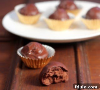 A delectable homemade chocolate truffle, with a small bite removed, sitting among other perfect truffles.