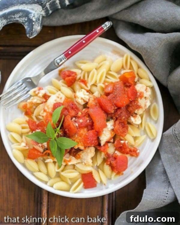 A close-up view of Chicken Feta Casserole served on a white plate with a red handled fork, highlighting the rich texture.