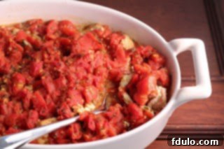 A hearty portion of Chicken Feta Casserole in a casserole dish with a serving spoon, inviting you to dig in.
