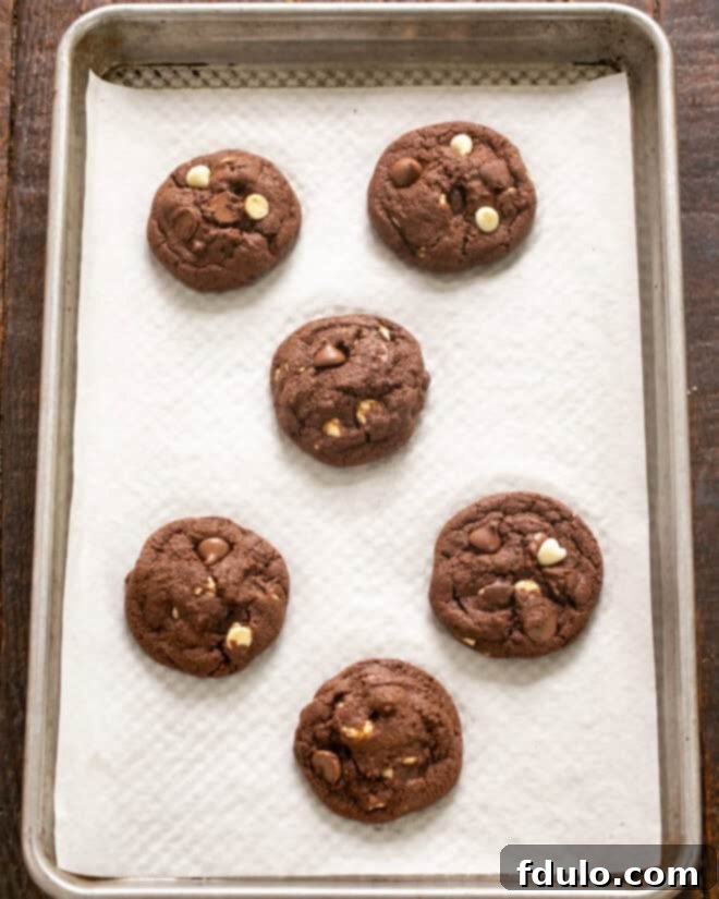 A baking sheet filled with cookie dough rounds, ready to be placed into the oven, indicating the next stage in the cookie baking process.