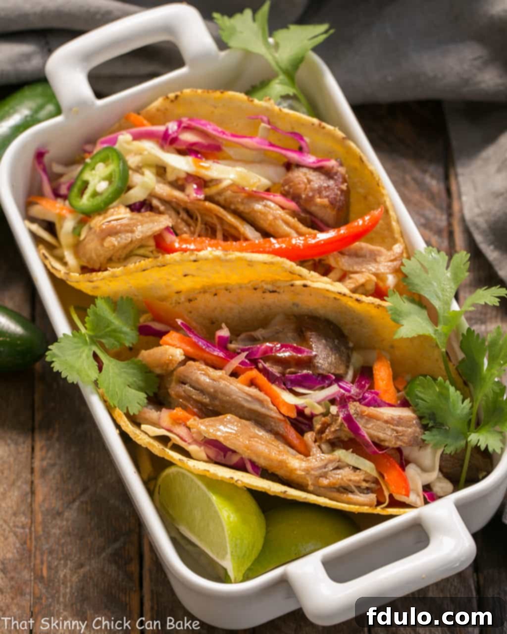 Slow Cooker Asian Pork Tacos with Cabbage Slaw displayed in a white casserole dish, highlighting the tender shredded pork.