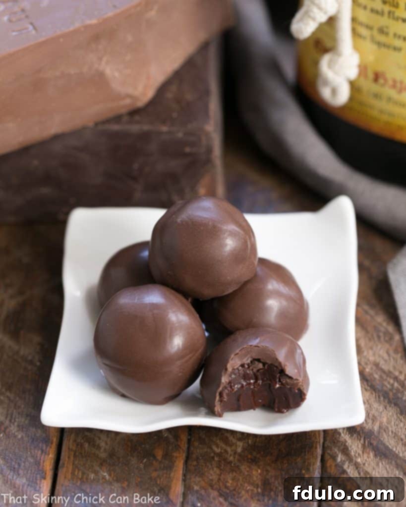 Chocolate Frangelico Truffles neatly arranged on a square white ceramic plate, highlighting their smooth, shiny coating.