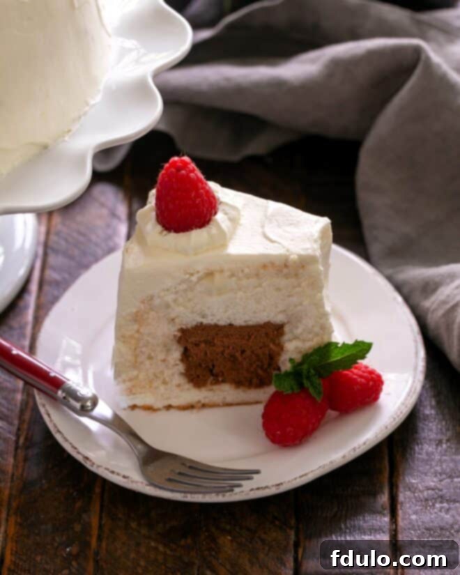 A beautifully frosted and sliced angel food cake, revealing the chocolate mousse filling, ready to be served and enjoyed with garnishes.