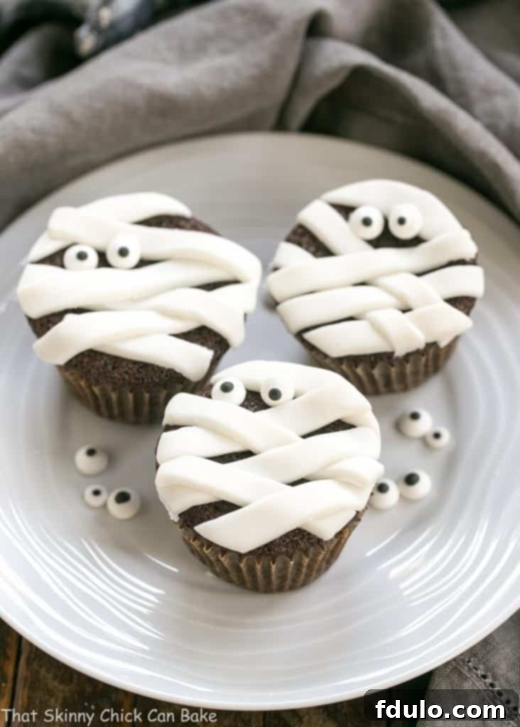 EASY Chocolate Mummy Cupcakes on a round white ceramic plate garnished with sugar eyes