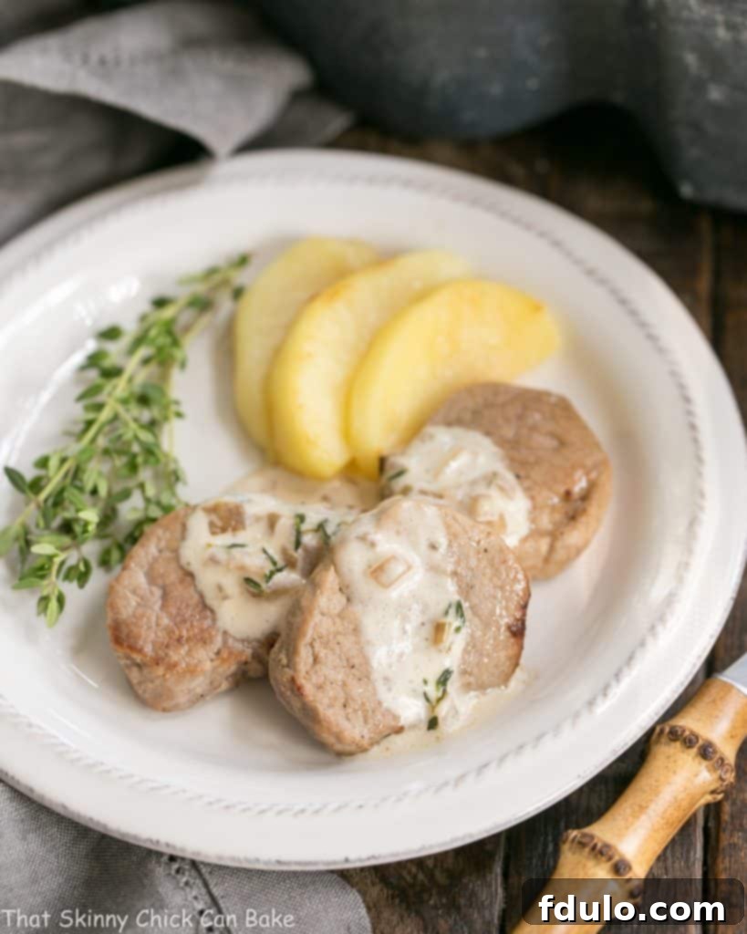 A close-up view of Apple Topped Pork Medallions with Calvados Cream Sauce, showcasing the rich sauce and tender pork.