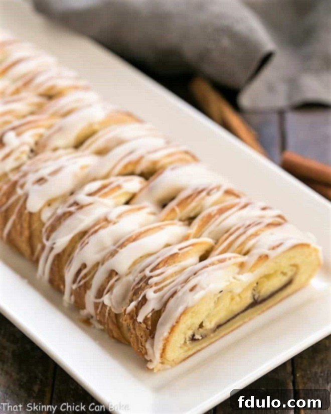 Braided Cinnamon Danish with Laminated Dough on a white tray, showcasing its flaky layers and glistening glaze.