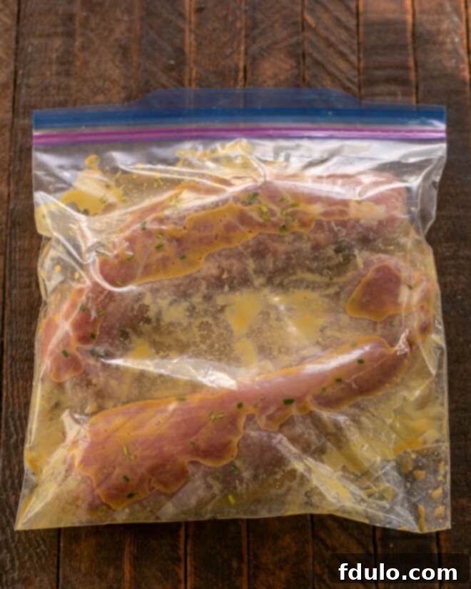 Adding pork to marinade in a Ziploc bag.