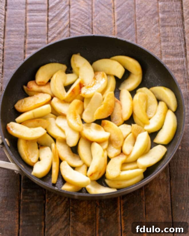 Sautéing sliced apples in a pan.