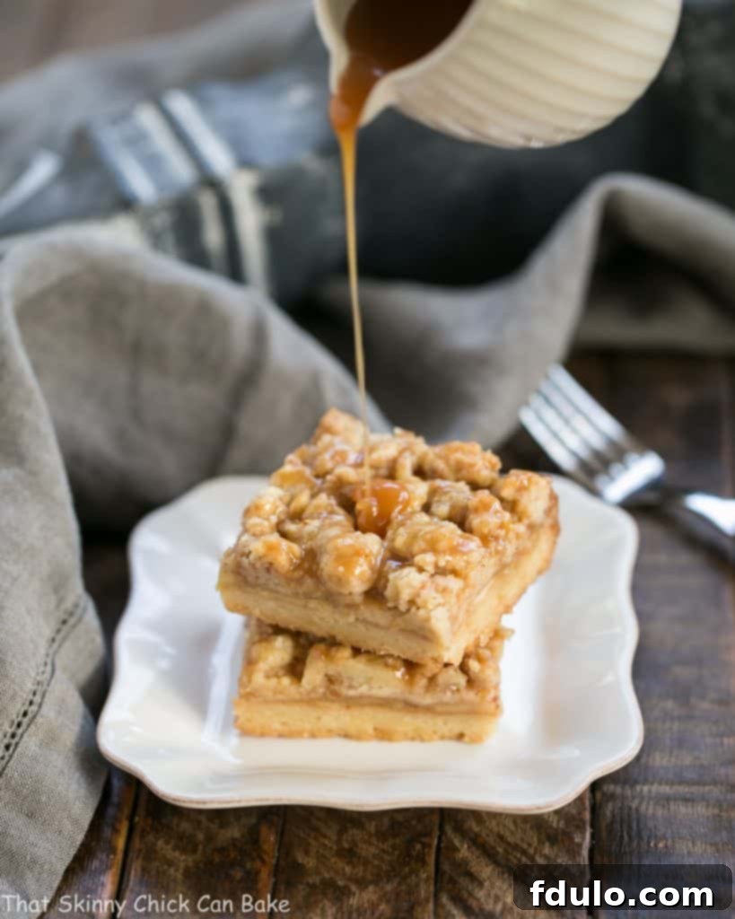 A stream of rich, golden caramel pouring over a stack of freshly baked Caramel Apple Pie Bars, highlighting their inviting texture.