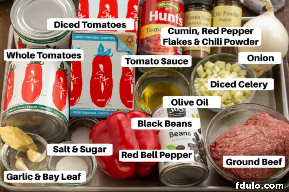 A colorful array of Black Bean Chili ingredients laid out on a sheet pan, including canned black beans, diced vegetables, various spices in small bowls, and ground beef, ready for preparation.