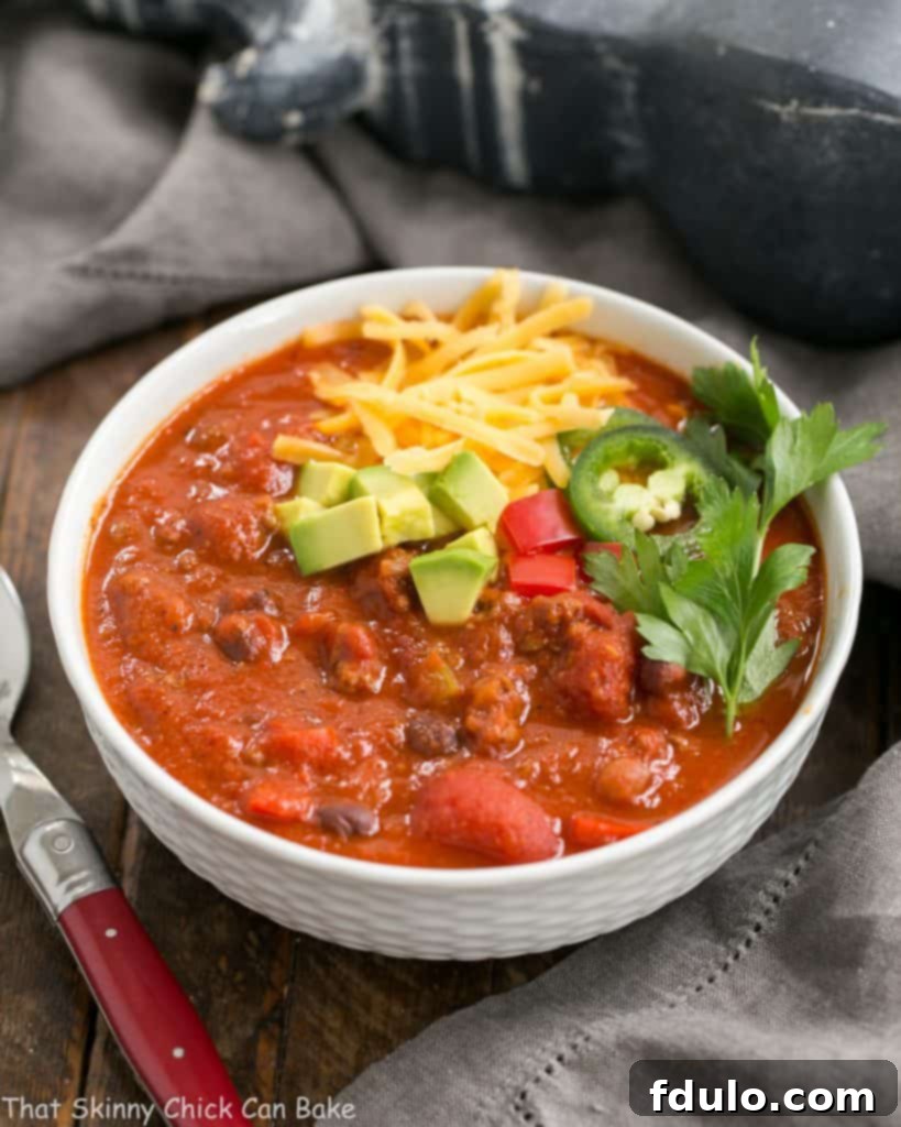 A beautifully garnished bowl of Easy Black Bean Chili, ready to be served, topped with a generous sprinkle of shredded cheese and fresh avocado slices, symbolizing a complete and delicious meal.