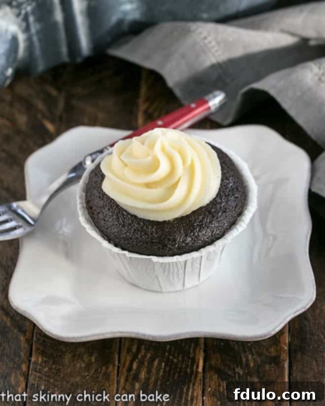 A black bottom cupcake on a square white plate, revealing its rich chocolate base and creamy filling.