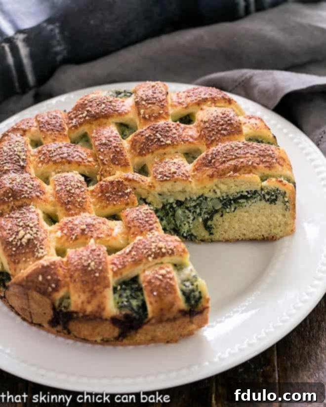 Spinach Torta Rustica with a wedge removed on a white serving plate, showcasing the vibrant green filling and golden lattice crust.
