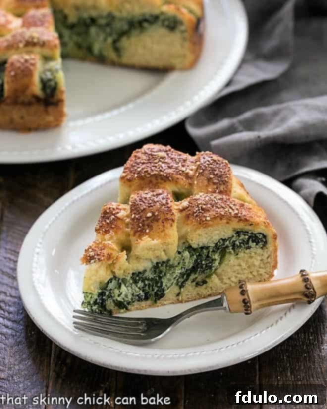Slice of Spinach Torta Rustica on a white plate with a bamboo handle fork, revealing the creamy spinach and ricotta filling.