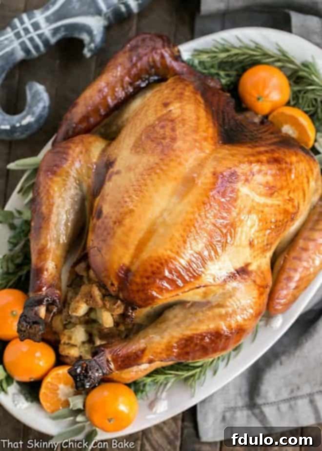Honey Brined Turkey on a white platter garnished with fresh herbs and vibrant oranges, showcasing its beautiful color and succulent texture.