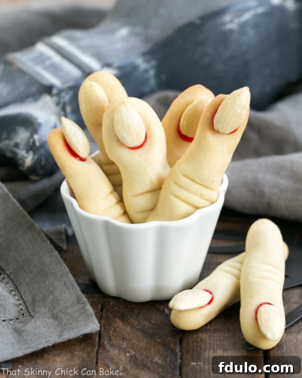Witches Fingers Cookies standing upright in a white ramekin, showcasing their detailed and creepy design.