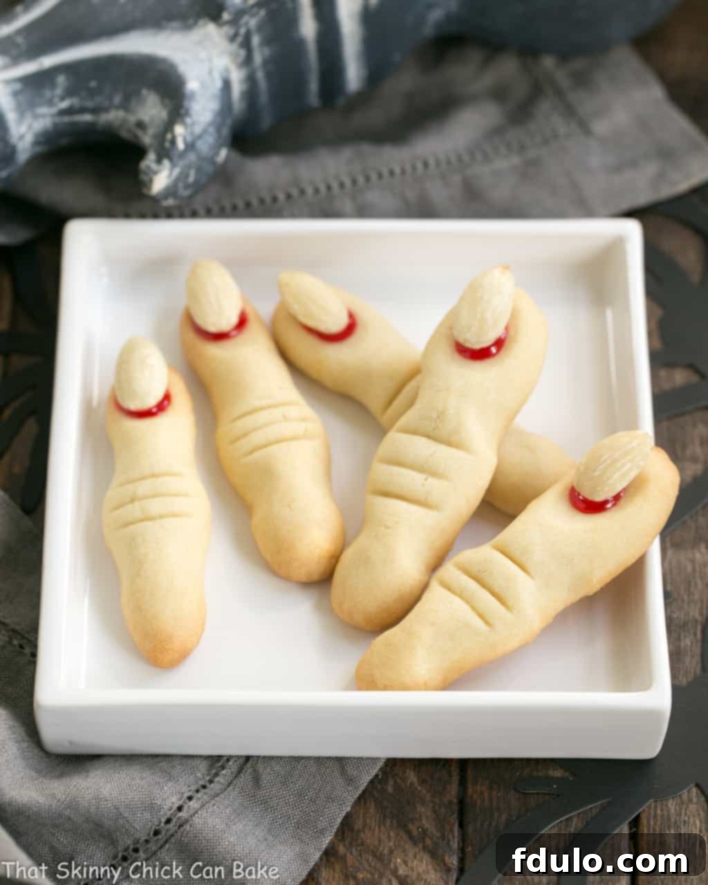 Several Witches Fingers Cookies fanned out on a rimmed white square plate, showcasing their varied shapes and details.
