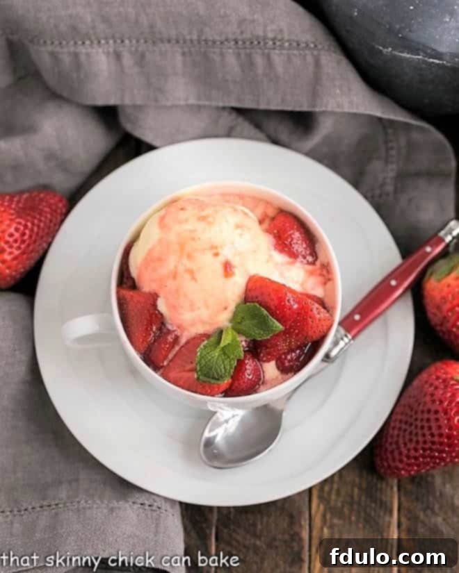 Cheesecake Ice Cream with Strawberry Sauce in a teacup viewed from above, garnished with fresh strawberries