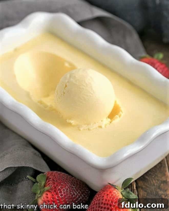 Cheesecake Ice Cream in a white ceramic loaf pan with fresh strawberries scattered around